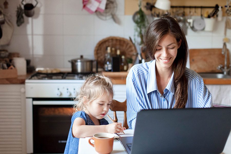 Personal Insurance - Happy Mother is Working From Home in the Kitchen While Her Daughter is Doing Her Homework